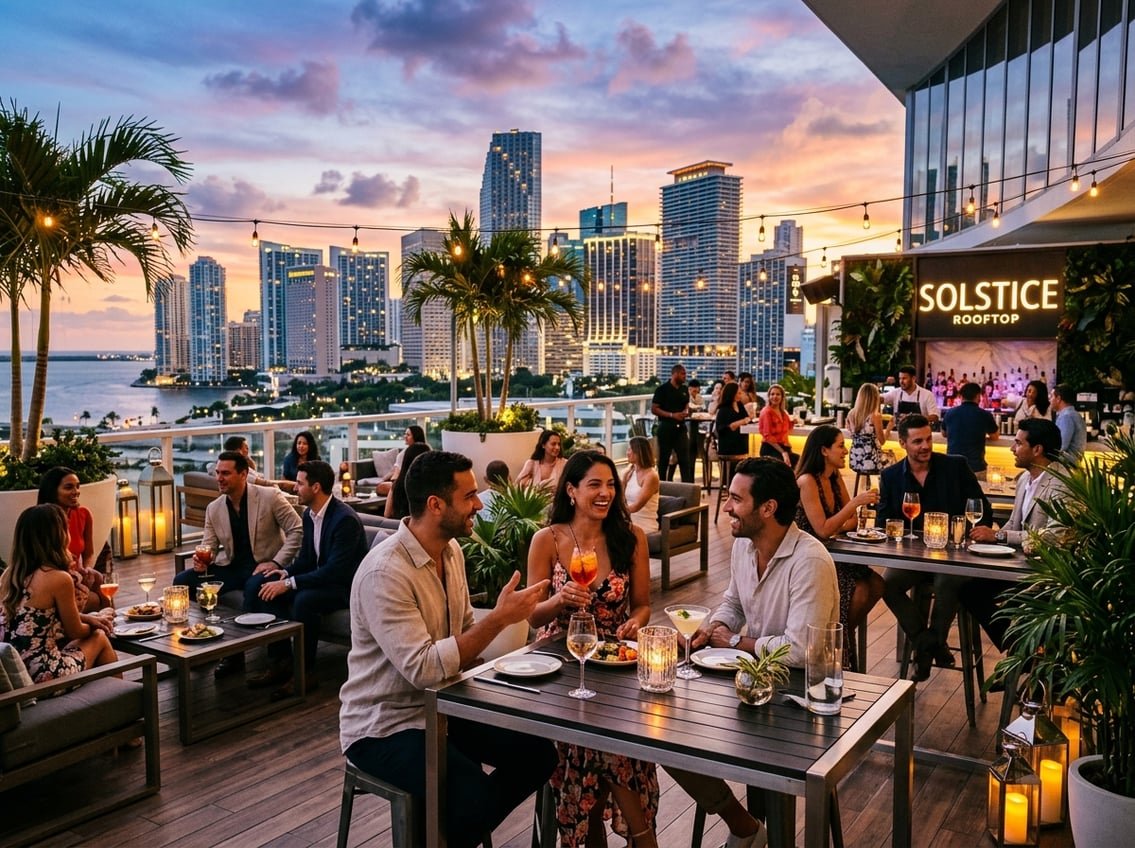 People enjoying drinks and dining on a rooftop terrace overlooking a city skyline at sunset.